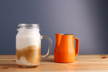 milk shake with coffee on wooden table and grey background. coffee shake with pitcher