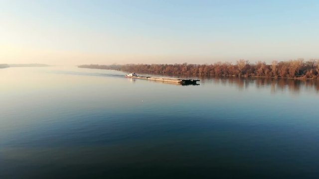 Drone video of tugboat pushing a barge on the river. Sunset sky.