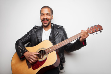 Handsome African man playing guitar wearing leather jacket isolated on white background.