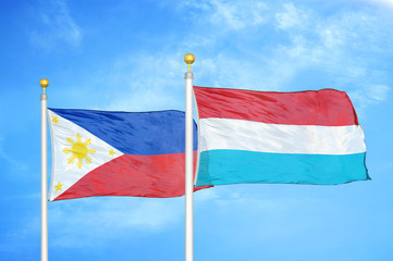 Philippines and Luxembourg two flags on flagpoles and blue cloudy sky