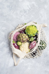 Different farm vegetables in a home string bag. Gray background. The concept of healthy eating.