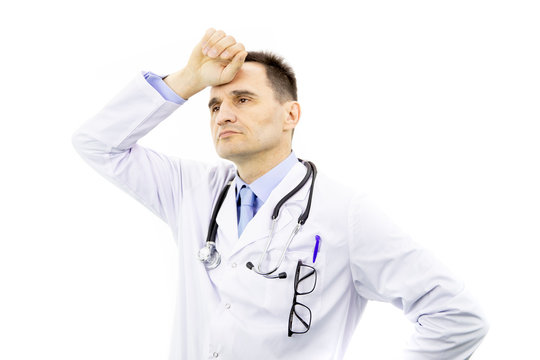 Portrait of handsome physician man with glasses in chest pocket wearing medical gown and stethoscope over isolated white background tired hold hands on head feeling fatigue. Headache concept.