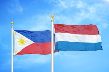 Philippines and Netherlands two flags on flagpoles and blue cloudy sky