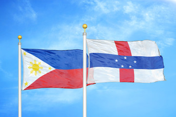 Philippines and Netherlands Antilles two flags on flagpoles and blue cloudy sky
