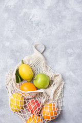 Different farm fruits in a home string bag. Gray background. The concept of healthy eating.