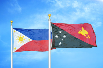 Philippines and Papua New Guinea two flags on flagpoles and blue cloudy sky
