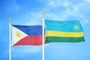 Philippines and Rwanda two flags on flagpoles and blue cloudy sky