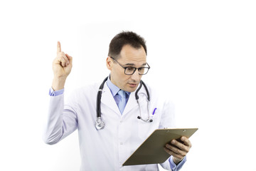 Fototapeta premium Pleasantly surprised male doctor in white coat and stethoscope holds thumb up checking patient's medical record on clipboard, isolated white background. Copy space. Health, recovery, treatment concept