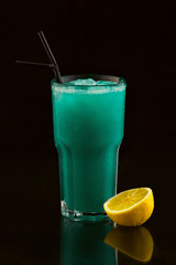 delicious blue green cocktail drink with lemon on the black background