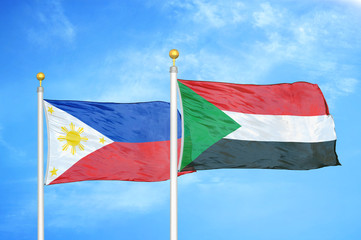 Philippines and Sudan two flags on flagpoles and blue cloudy sky