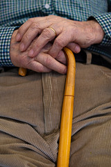 Elderly man resting in a rocking chair with a walking stick