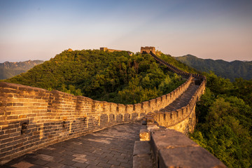Fototapeta na wymiar Golden sunlight blankets the Great Wall of China on a moody, cloudy, afternoon near Beijing, China.