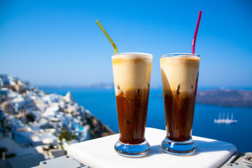 Coffee espresso freddo with a wide sea of caldera in greek cafe. Greece, Santorini island in...