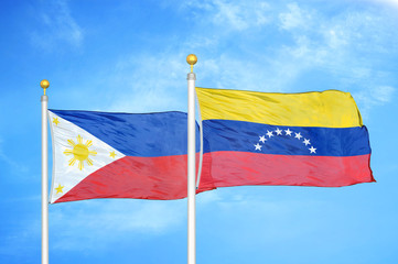 Philippines and Venezuela two flags on flagpoles and blue cloudy sky