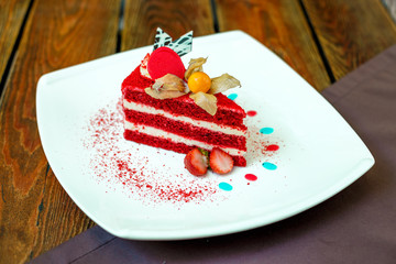 red velvet cake on a plate with strawberries on a wooden table