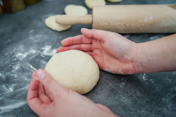 Close up on hand of unknown caucasian woman female girl making bread knead the dough kneading on the kitchen table at home top view