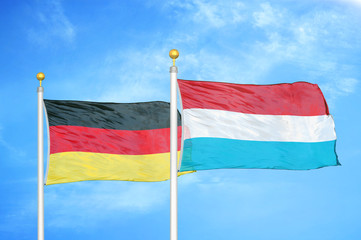 Germany and Luxembourg two flags on flagpoles and blue cloudy sky