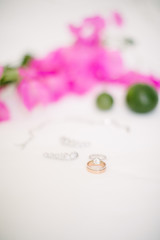 Wedding rings and jewelry. On a white background and pink bougainvillea leaves and lime. 