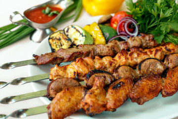 assorted of kebabs with grilled vegetables, pickled onions, herbs and spicy sauce