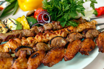 assorted of kebabs with grilled vegetables, pickled onions, herbs and spicy sauce