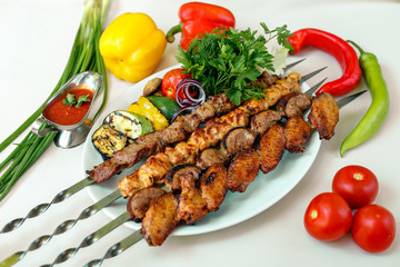 assorted of kebabs with grilled vegetables, pickled onions, herbs and spicy sauce