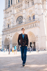 Fototapeta na wymiar a young man poses against the backdrop of Notre Dame Cathedral in Paris.
