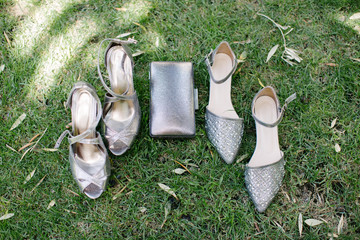Gray heels and gray shiny handbag. On the grass.