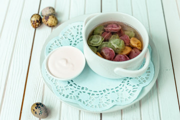 rainbow dumplings for children on a wooden background with flowers and quail eggs
