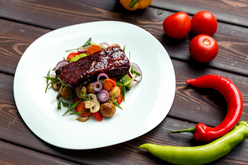A calf steak with a young potato and juicy vegetables on a wooden background