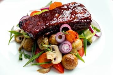A calf steak with a young potato and juicy vegetables on a wooden background