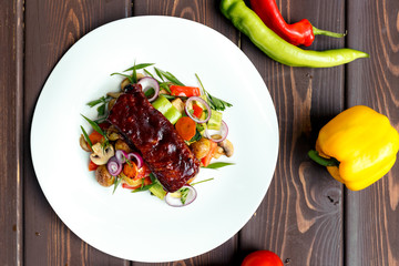 A calf steak with a young potato and juicy vegetables on a wooden background