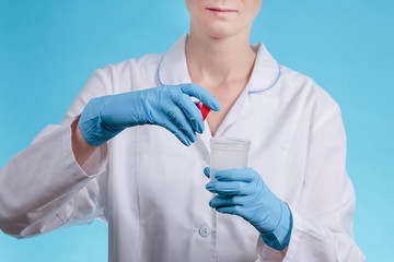 a doctor in blue gloves opens a jar for collecting tests as an illustration of preparation for surgery