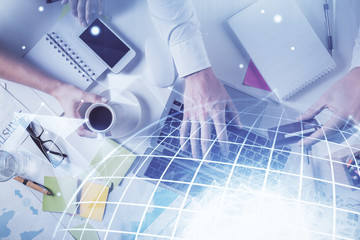 Multi exposure of man's hands typing over computer keyboard and world map hologram drawing. Top view. Technology concept.