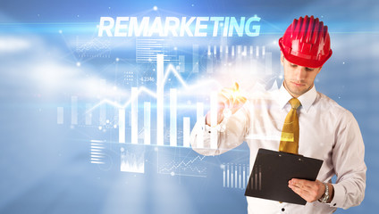 Handsome businessman with helmet drawing REMARKETING inscription, architecture business plan concept