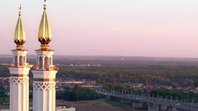 Minaret of Ar-Raheem mosque in Ufa city with gilded towers and cresent on top with main bridge entrance to capital of Bashkortostan at background