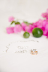 Wedding rings and jewelry. On a white background and pink bougainvillea leaves and lime.