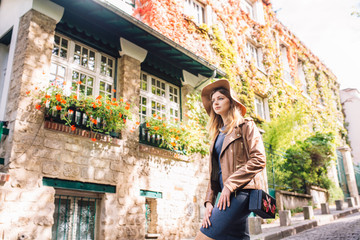 A beautiful young woman in a brown jacket walks in the early morning on the famous Montmartre hill...