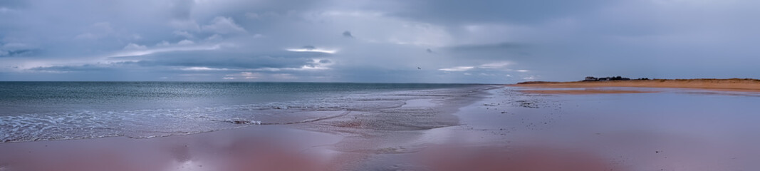 Brora beach with the tide going out and with reflections in the wet sand