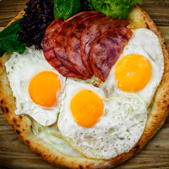 Bacon and eggs on a wheat cake with greens for lunch