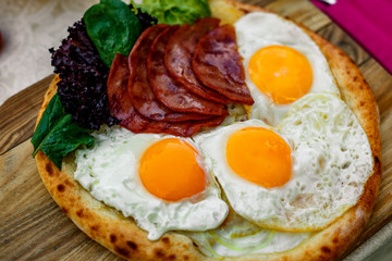 Bacon and eggs on a wheat cake with greens for lunch