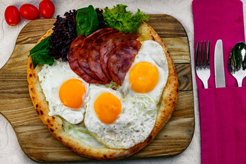 Bacon and eggs on a wheat cake with greens for lunch