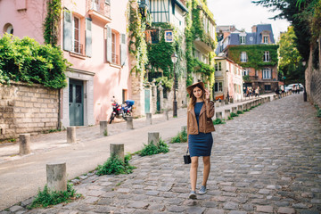 Fototapeta na wymiar A beautiful young woman in a brown jacket walks in the early morning on the famous Montmartre hill in Paris