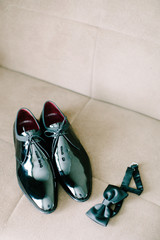 Black patent leather wedding shoes. Bow tie. Wedding reparations details. Indoor and close up.