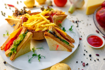 sandwiches with fresh vegetables and chicken with fried potatoes on a white tablecloth