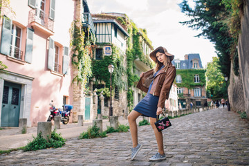 A beautiful young woman in a brown jacket walks in the early morning on the famous Montmartre hill in Paris