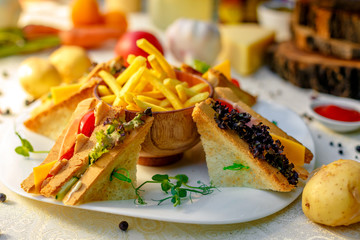 sandwiches with fresh vegetables and chicken with fried potatoes on a white tablecloth
