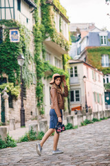 Obraz na płótnie Canvas A beautiful young woman in a brown jacket walks in the early morning on the famous Montmartre hill in Paris