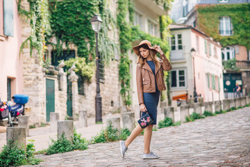 A beautiful young woman in a brown jacket walks in the early morning on the famous Montmartre hill in Paris