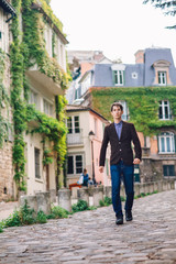 a man in a jacket and jeans walks in Montmartre, Paris