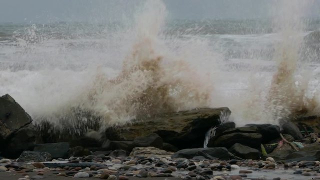 Giant stormy crashing waves breaking into rock stones